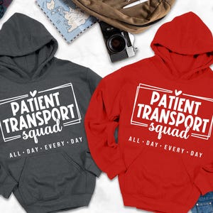 May include: Two hooded sweatshirts, one charcoal gray and one red, with the text "PATIENT TRANSPORT squad ALL DAY EVERY DAY" in a white rectangular box. The red sweatshirt is paired with blue jeans.