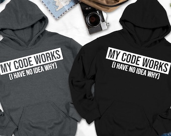 Peut inclure: Deux sweats à capuche, un gris anthracite et un noir, sont présentés. Chacun affiche le texte "MY CODE WORKS (I HAVE NO IDEA WHY)" dans un rectangle blanc. Les sweats ont une poche avant et une capuche. Le bas de l'image indique "HOODIE COLORS MAY LOOK SLIGHTLY DARKER OR LIGHTER IN PHOTOS."