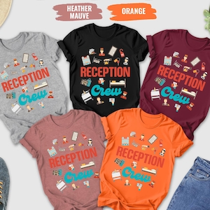 May include: A collection of t-shirts in various colors, including gray, black, maroon, heather mauve, and orange. Each shirt features the text "RECEPTION Crew" in a colorful design with hotel-themed graphics. The shirts are displayed with accessories.