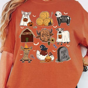 A woman wearing an orange t-shirt with various Halloween-themed illustrations, including animals, pumpkins, and other spooky elements.