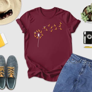 a t - shirt with a dandelion on it next to a pair of