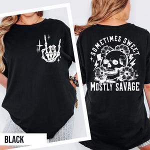 a black t-shirt with a graphic design on the back, including a skull and floral elements, along with the text "Sometimes Sweet Mostly Savage".