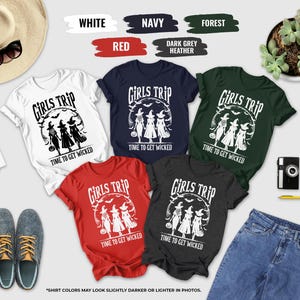 a collection of t-shirts with the phrase "Girls Trip" printed on them, along with various accessories such as sunglasses, a hat, a camera, and a plant.