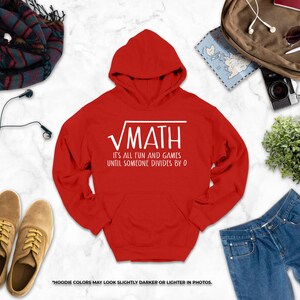 a red hoodie with a white text design, a pair of brown shoes, a pair of blue jeans, a scarf, a camera, a map, and some plants.