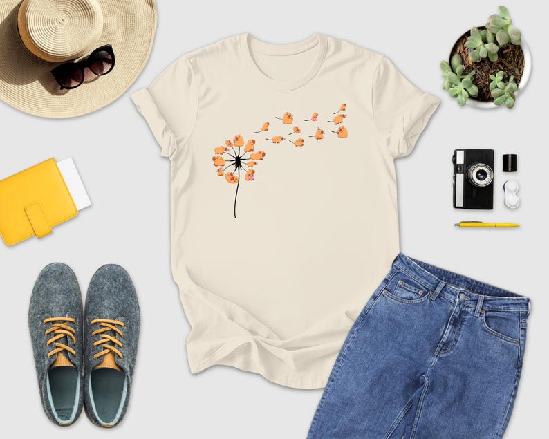 a t - shirt with a dandelion on it next to a pair of
