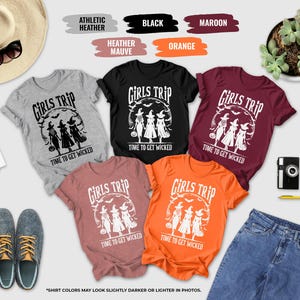 a collection of Halloween-themed t-shirts, a hat, sunglasses, a camera, a potted plant, and some other items, all arranged on a white background.