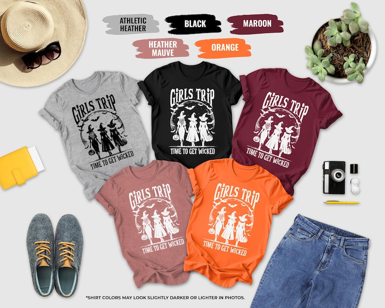a collection of Halloween-themed t-shirts, a hat, sunglasses, a camera, a potted plant, and some other items, all arranged on a white background.