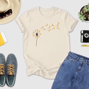 a t - shirt with a dandelion on it next to a pair of