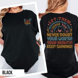 May include: Black t-shirt with the text "LET THEM" on the front and a graphic on the back that reads "LET THEM MISUNDERSTAND YOU, JUDGE YOU, GOSSIP ABOUT YOU. NEVER DOUBT YOUR WORTH! YOUR BEAUTY! KEEP SHINING!"
