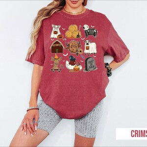 A woman wearing a red t-shirt with various Halloween-themed illustrations, including pumpkins, bats, and other spooky and festive elements.