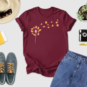 a t - shirt with a dandelion on it next to a pair of