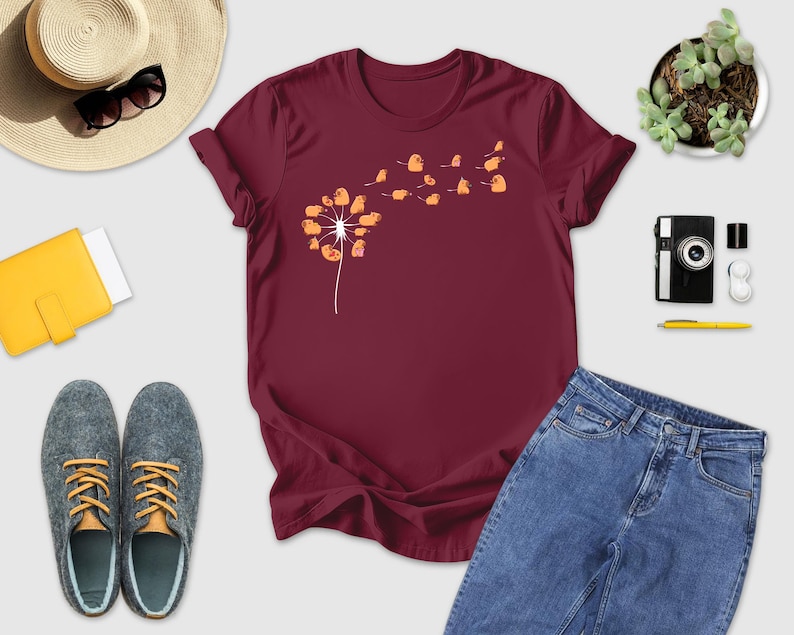 a t - shirt with a dandelion on it next to a pair of