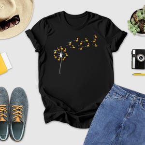 a t - shirt with a dandelion on it next to a pair of