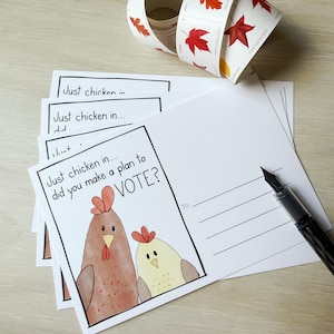 May include: A stack of white postcards with a cartoon chicken illustration and the text "Just chicken in... did you make a plan to VOTE?". A roll of leaf-themed stamps and a fountain pen are also present.