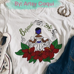 May include: White t-shirt with a digital design of a woman in a white dress with red hibiscus flowers and green leaves. The text "Borícua" is written in a cursive font above the woman.