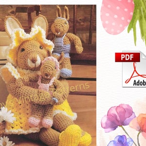 May include: Crochet pattern for three bunny dolls. The mother bunny is wearing a yellow dress with a pink and white trim. The baby bunny is wearing a pink dress with a white trim. The father bunny is wearing blue overalls and a blue shirt. The pattern is available as a PDF download.