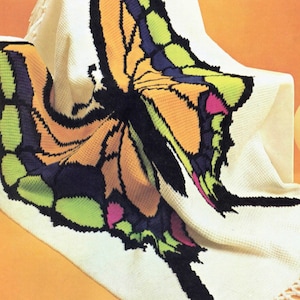 May include: A white crocheted throw blanket with a colorful butterfly design. The butterfly has orange, green, blue, black, and pink accents.