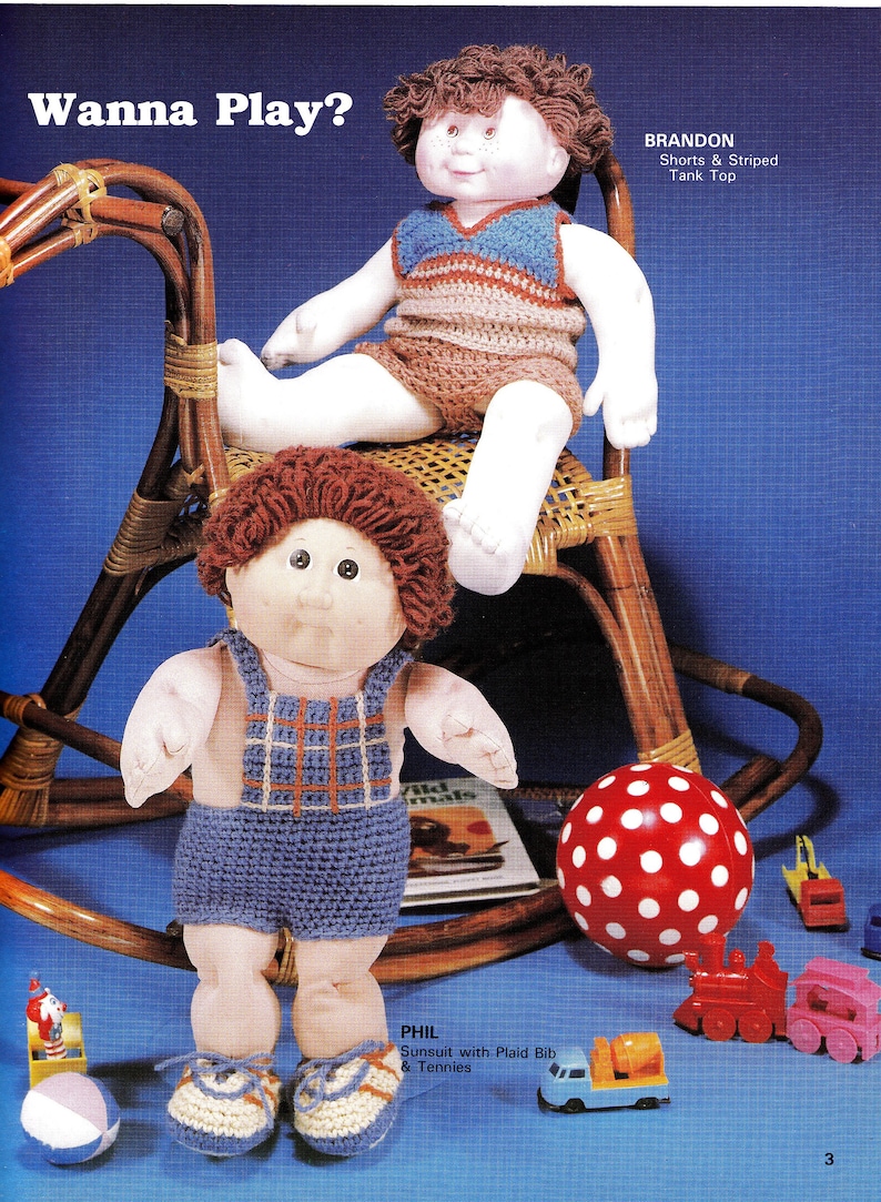 May include: Two Cabbage Patch Kids dolls dressed in crocheted outfits. The doll on the left is wearing a blue and orange overalls and the doll on the right is wearing a striped tank top and shorts. The dolls are sitting on a rocking chair and playing with toys.