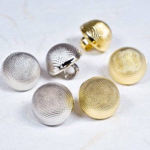 May include: Five round buttons with a textured surface. Two buttons are gold and three buttons are silver.
