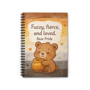 Puede incluir: Un cuaderno con espiral con una ilustración en acuarela. La portada presenta un oso de dibujos animados sosteniendo un tarro de miel, con el texto "Fuzzy, fierce, and loved. Bear Pride." El fondo tiene un degradado de marrón, amarillo y gris.