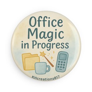 Op de afbeelding: Ronde knoop met de tekst "Office Magic in Progress" in teal. De knoop toont illustraties van een dossier, een toverstaf, een mok en een telefoon. De achtergrond heeft een aquareleffect met lichtblauwe en gele tinten.