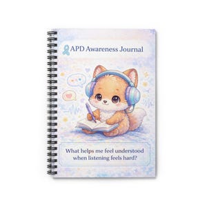 May include: A spiral-bound notebook with a cover illustration of a cartoon fox wearing headphones and writing. The cover reads "APD Awareness Journal" and includes the text "What helps me feel understood when listening feels hard?"