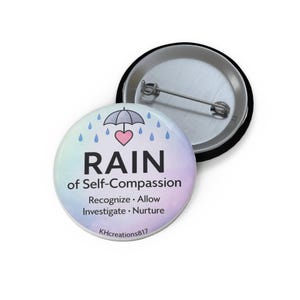 May include: A round button with the text "RAIN of Self-Compassion" and the words "Recognize, Allow, Investigate, Nurture". The button has a pastel background with an umbrella, heart, and raindrops design.