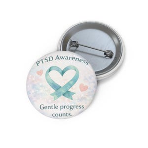 May include: A circular badge featuring a teal ribbon heart, the text 'PTSD Awareness', and 'Gentle progress counts.' The design includes pink hearts on a pastel watercolour background.