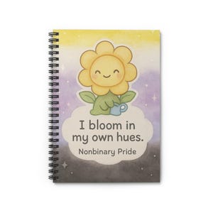 以下が含まれることがあります： 漫画のイラストが描かれたスパイラル綴じノート。花は黄色で、笑顔の顔、緑の葉、じょうろが描かれています。ノートの表紙には「I bloom in my own hues. Nonbinary Pride.」と書かれています。