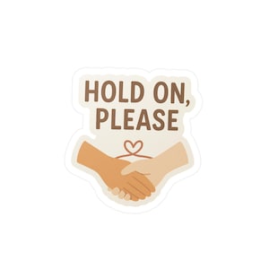 Pode incluir: Um autocolante com o texto "HOLD ON, PLEASE" em letras castanhas. O autocolante apresenta duas mãos a apertar-se, com um símbolo de coração por cima. As mãos são em tons de bege e creme.