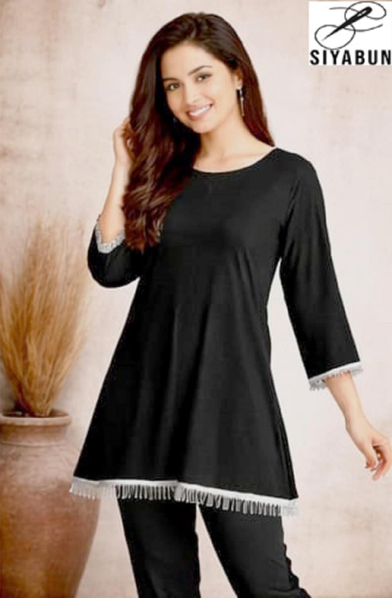 May include: Black tunic and pants set. The tunic has a round neckline and three-quarter sleeves with white lace trim. The pants are black. The logo "SIYABUN" is in the upper right corner.