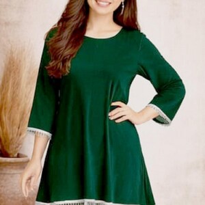 May include: A dark green tunic and leggings set with white lace trim. The tunic has three-quarter sleeves and a rounded neckline. The logo "SIYABUN" is in the upper right corner. The model is smiling.