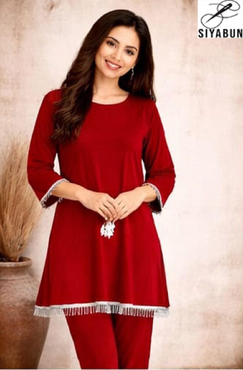 May include: A red two-piece pajama set. The top has long sleeves with white trim and a flared hem with white fringe. The matching pants are a solid red. The image includes the brand logo "SIYABUN" in the upper right corner.