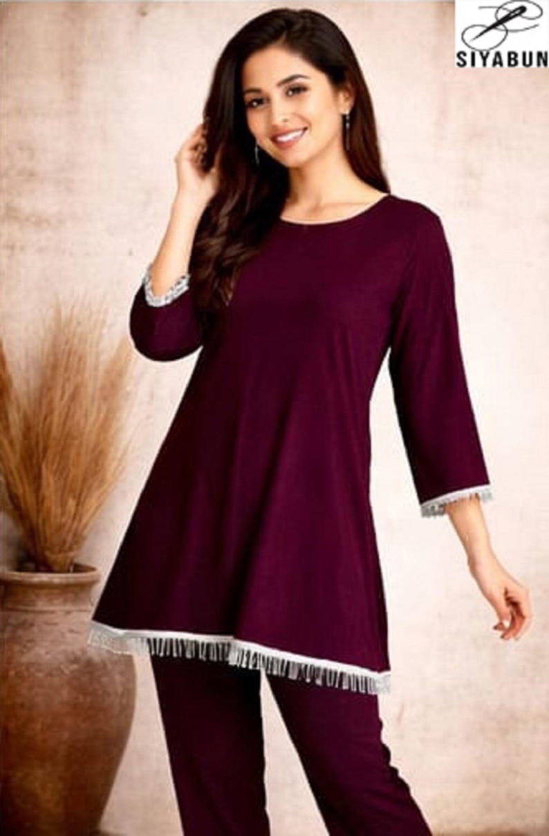 May include: Burgundy-colored pajama set. The top has a round neckline and three-quarter sleeves, trimmed with white lace. The matching pants complete the set. The image includes the brand logo "SIYABUN".
