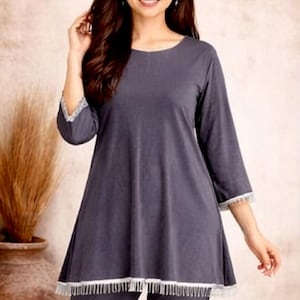May include: A dark gray pajama set with a tunic-style top and matching pants. The top has three-quarter sleeves and a white fringe trim at the hem and sleeve cuffs. The image includes the brand logo "SIYABUN".