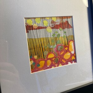 May include: Abstract watercolor painting in a white matted frame. The painting features a mix of yellow, orange, red, and green colors in a geometric pattern.