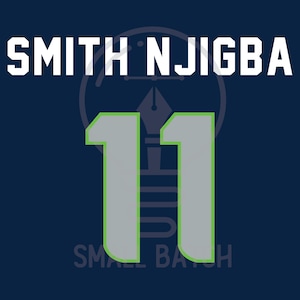 Puede incluir: Diseño gráfico azul marino con el nombre "SMITH NJIGBA" en letras blancas en bloque sobre el número "11" en gris con un contorno verde. Las palabras "SMALL BATCH" están en la parte inferior.
