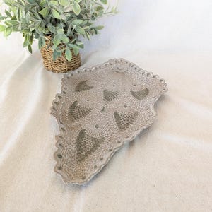 May include: A white ceramic serving tray with a decorative green pattern. The tray is shaped like a leaf and has a scalloped edge.