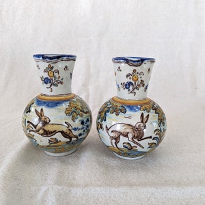 May include: Two ceramic vases with a blue and yellow floral design and a brown rabbit illustration. The vases are round with a white background.