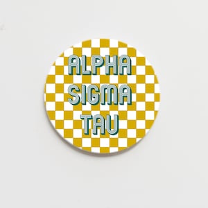 May include: A round, white sticker with a checkered pattern in yellow and white. The text "ALPHA SIGMA TAU" is written in green on the sticker.