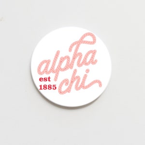 May include: White round coaster with a pink rope design that spells out "alpha chi" and the text "est 1885" in red.