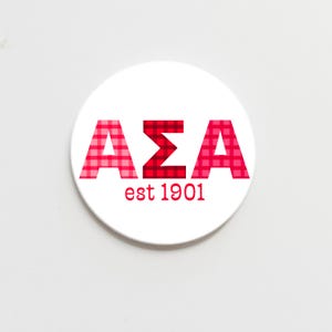May include: White round sticker with red and pink gingham letters spelling "AEA est 1901".