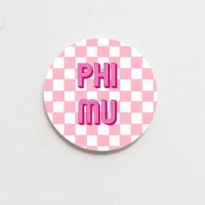 May include: A pink and white checkered round sticker with the text "PHI MU" in a pink retro font.