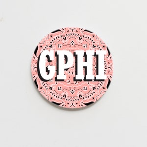 May include: A pink and black round coaster with a bandana pattern and the text "GPHI" in white.