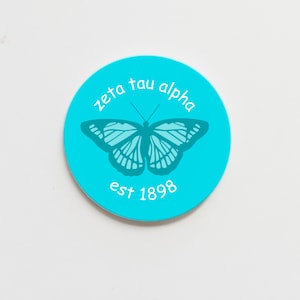 May include: A turquoise blue circle sticker with a white butterfly silhouette and the text "zeta tau alpha est 1898".