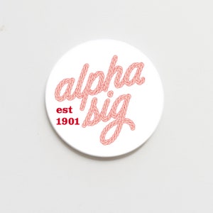 May include: White round sticker with the text "alpha sig" in pink rope lettering and "est 1901" in red text.