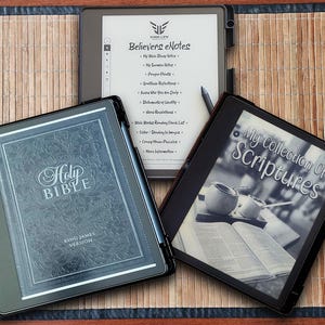 May include: Two black e-readers with covers. The left e-reader displays a Holy Bible cover with the words "Holy Bible" and "King James Version". The right e-reader displays a cover with the words "My Collection of Scriptures".