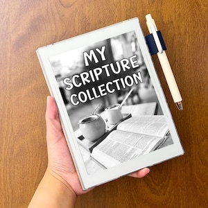 May include: A white digital tablet featuring the text MY SCRIPTURE COLLECTION on its screen, which displays a black and white image of an open book and two small containers. A cream-colored pen is attached to the side with a dark blue holder.