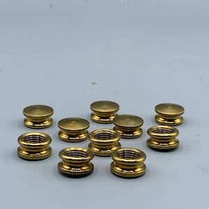May include: Ten gold-colored metal caps with a threaded center hole. The caps have a rounded top and a slightly flared base.