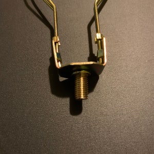May include: A gold metal lamp harp with a threaded screw for attaching a lampshade.